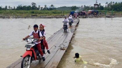 Siswa melintasi jembatan kayu darurat di Sawang, Aceh Utara, di tengah rencana pembangunan jembatan permanen