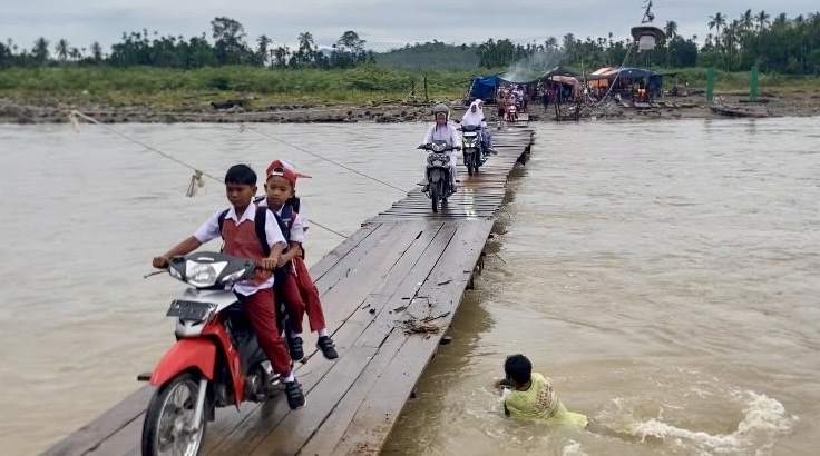Siswa melintasi jembatan kayu darurat di Sawang, Aceh Utara, di tengah rencana pembangunan jembatan permanen